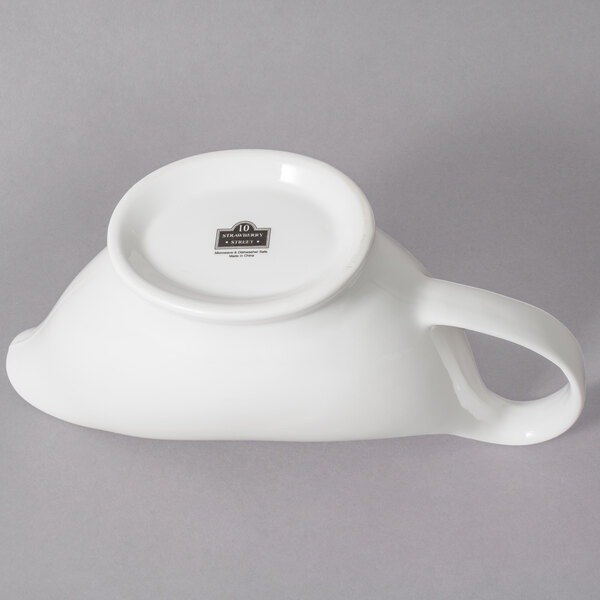 A white porcelain gravy boat with a handle and a spout.