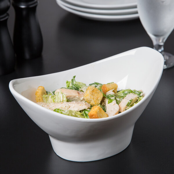 A white 10 Strawberry Street Whittier porcelain oval bowl filled with salad.