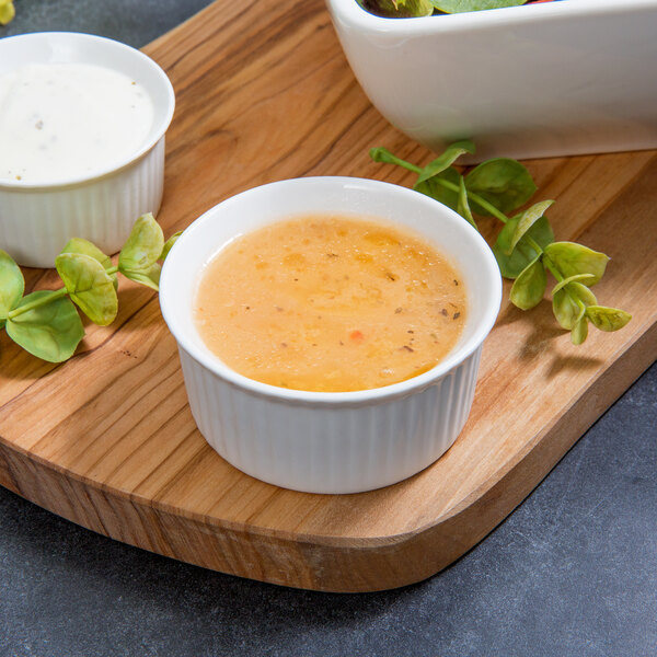 A 10 Strawberry Street white porcelain fluted ramekin filled with white liquid on a wood surface.