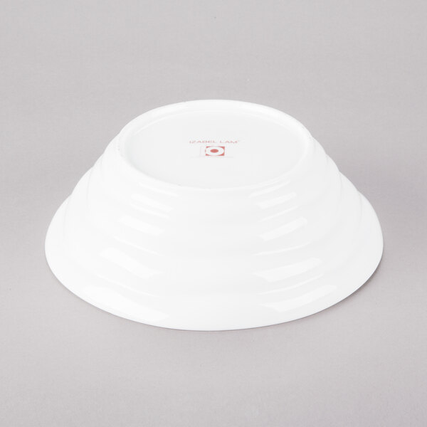 A 10 Strawberry Street bright white porcelain bowl with a ripples pattern on the rim on a gray surface.
