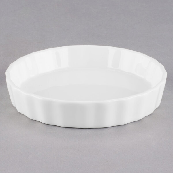 A white porcelain fluted creme brulee dish with a rim.