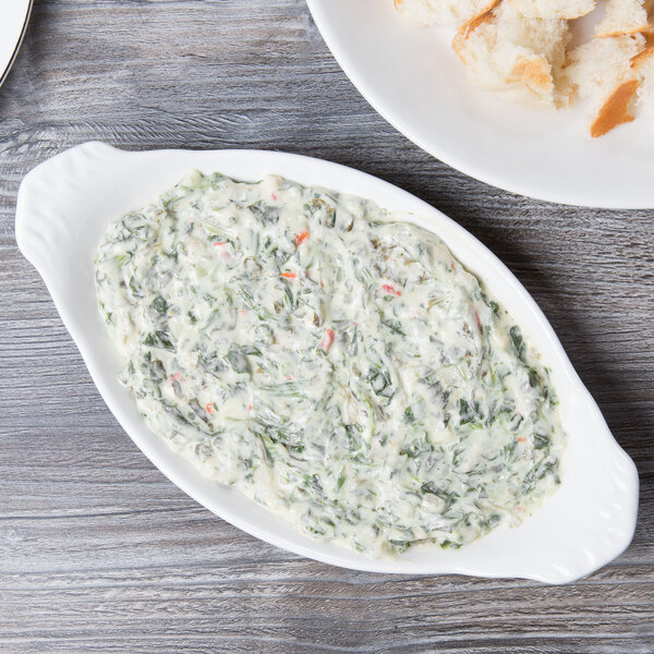 A 10 Strawberry Street white porcelain oval rarebit dish with spinach dip and bread.