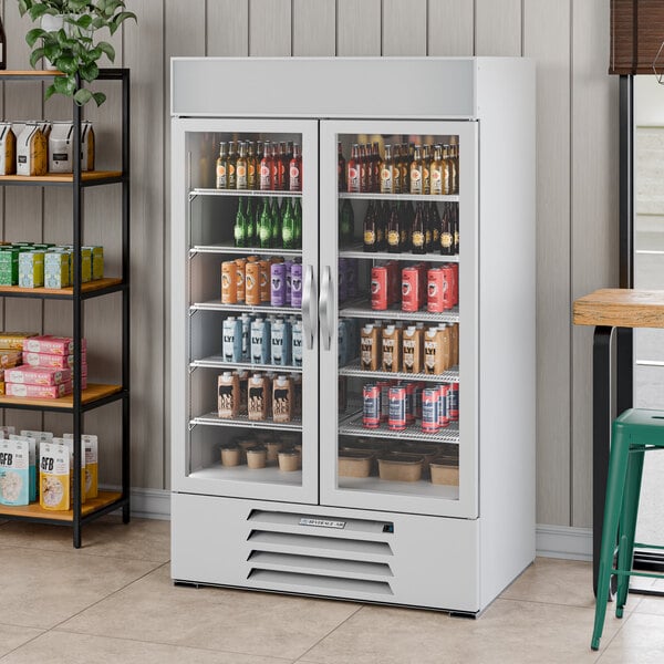 A white two-section glass door merchandiser refrigerator filled with various beverages.