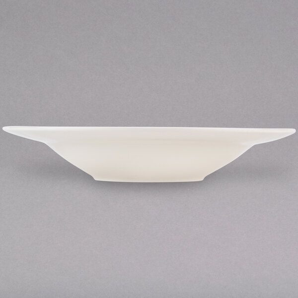 A Tuxton eggshell white china pasta bowl on a gray background.