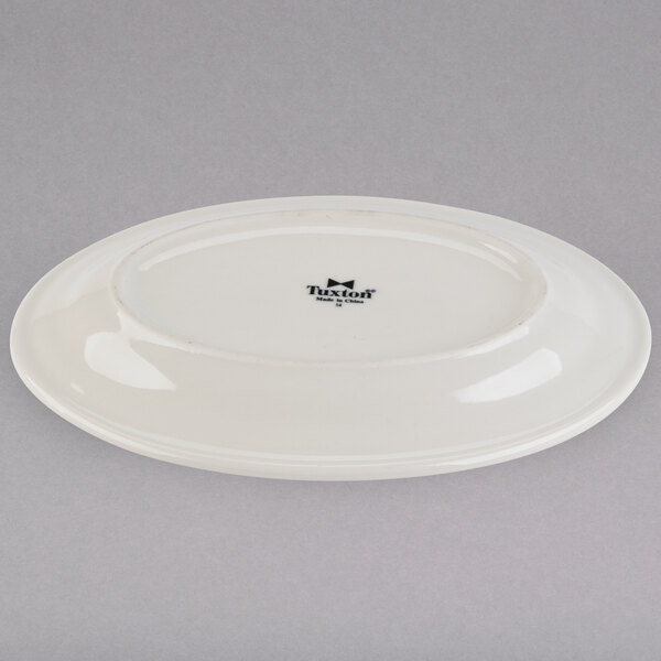 A white Tuxton oval china platter with a wide black rim.