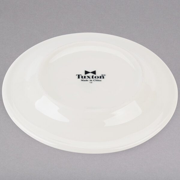A white Tuxton Reno china plate with black text reading "Tuxton"