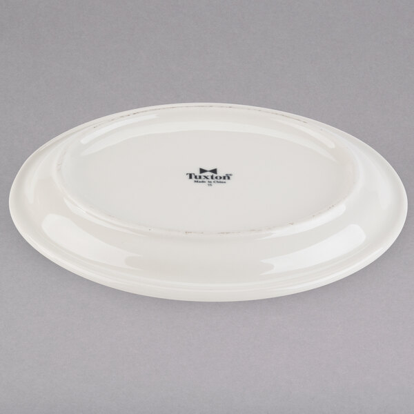 A white Tuxton china platter with a narrow black rim.
