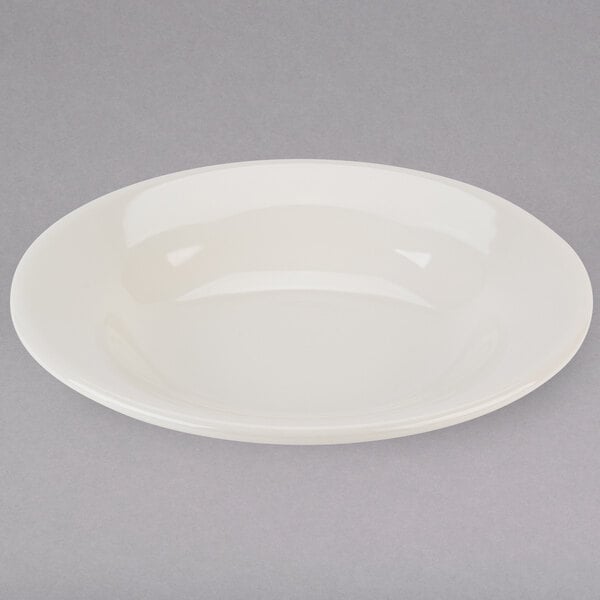 A white Tuxton China bowl with a rim on a gray surface.