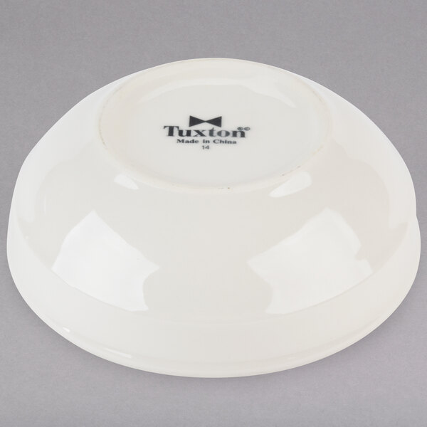 A white Tuxton china bowl with black text on it.