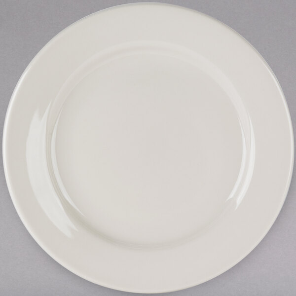 A Tuxton Reno ivory china plate with a wide rim on a gray background.