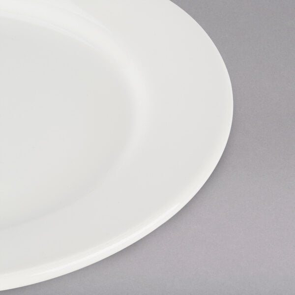 A close-up of a Tuxton Reno ivory china plate with a wide white rim.