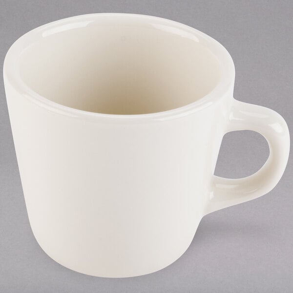 A Tuxton eggshell white tall china cup with a handle.