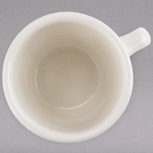 A white Tuxton tall china cup with a handle.