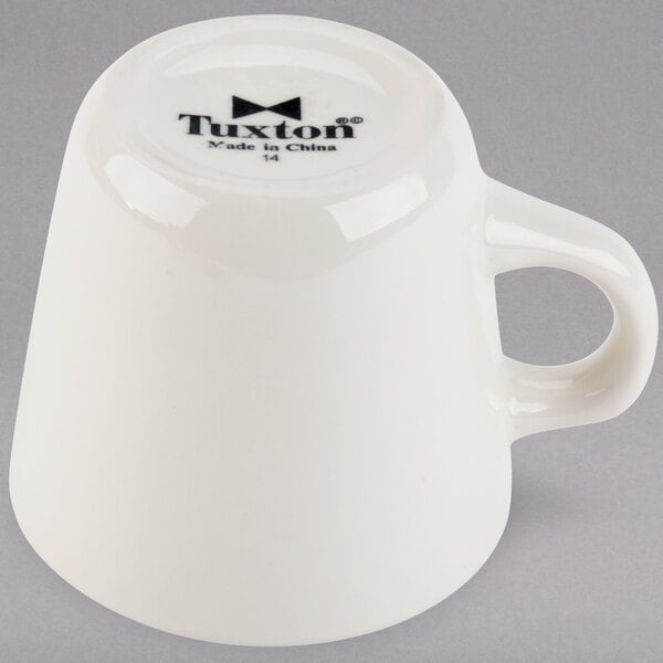 A Tuxton eggshell white china cup with a handle.