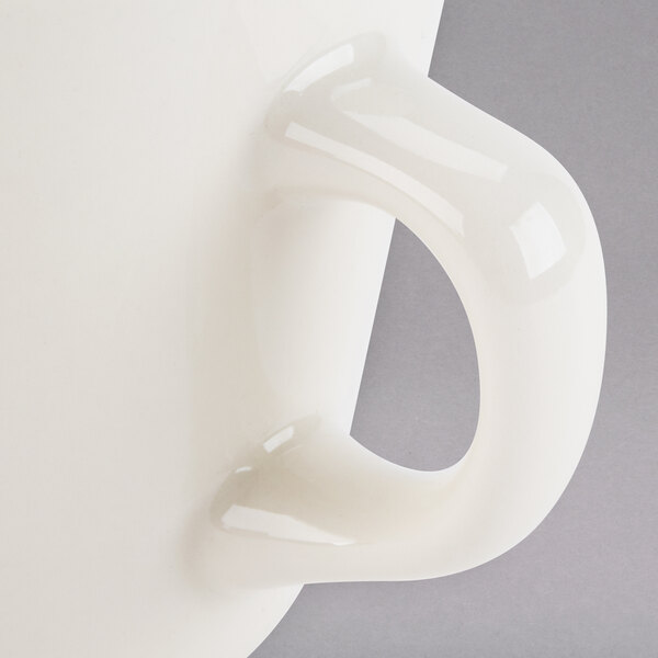 A white Tuxton tall china cup with a handle.