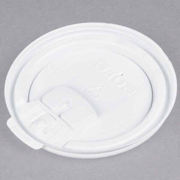 A close up of a Solo white plastic tear tab lid with a hole in it.