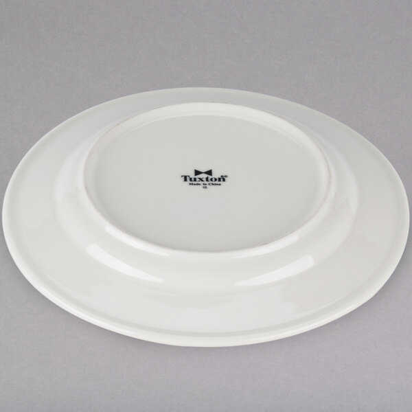 A Tuxton Reno ivory china plate with a wide rim with a black edge and a white rim.