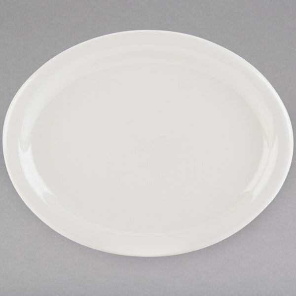 A white Tuxton Nevada oval china platter with a narrow rim on a gray surface.