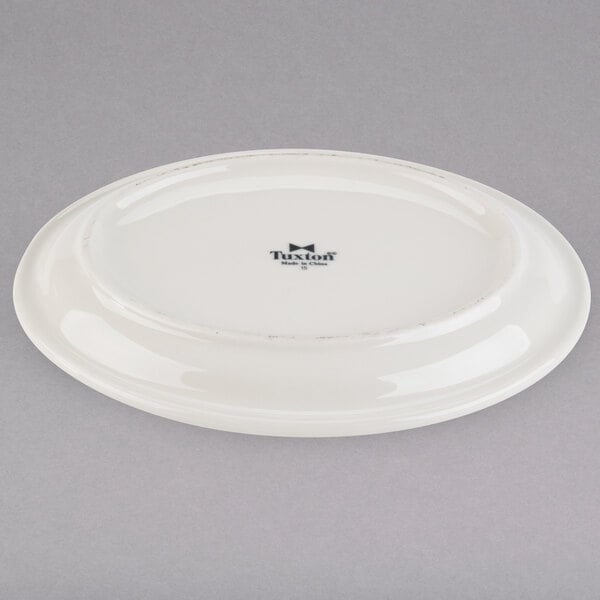 A white Tuxton oval china platter with a narrow black rim.
