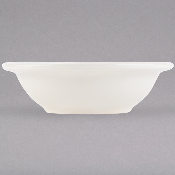 A white Tuxton china bowl with a white rim on a white surface.