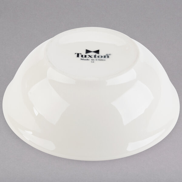 A white Tuxton china nappie bowl with black text on it.