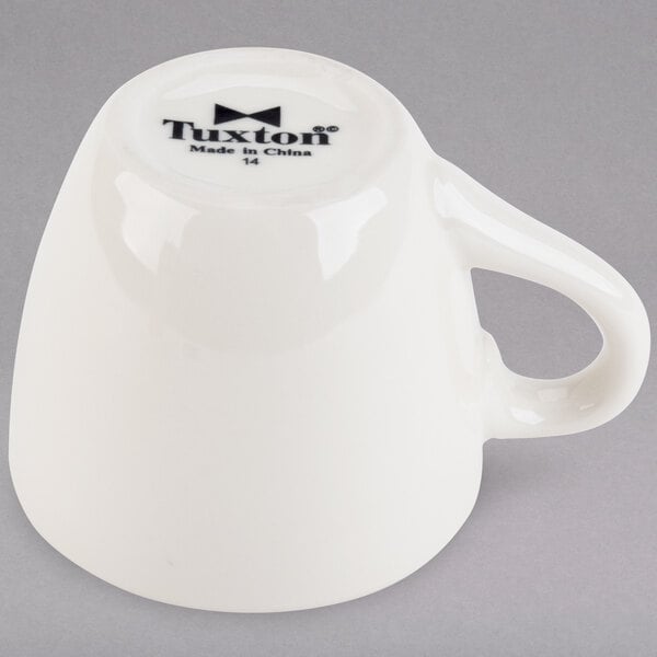A white Tuxton espresso cup with a handle.