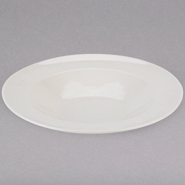 A Tuxton eggshell china pasta bowl with a shadow on a white background.