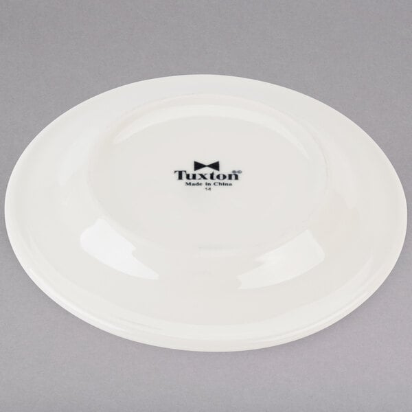 A Tuxton Reno ivory china plate with black text reading "Tuxton" on it.