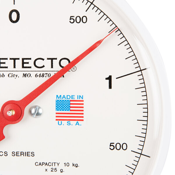 A close up of a white and red Cardinal Detecto hanging scale.