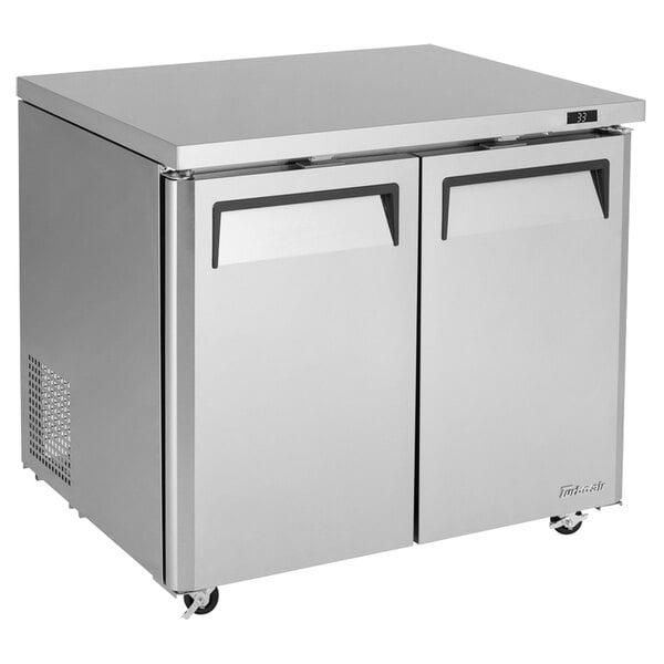 A silver Turbo Air undercounter refrigerator with two black doors.