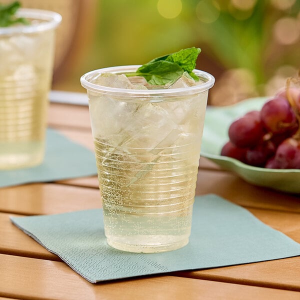 A clear plastic cup with ice and a green leaf in it.
