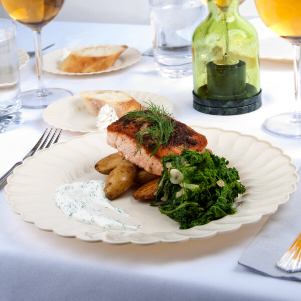 A Fineline Flairware ivory plastic plate with food on a white table.