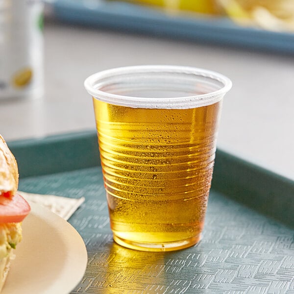 A plastic cup with a drink in it on a tray.