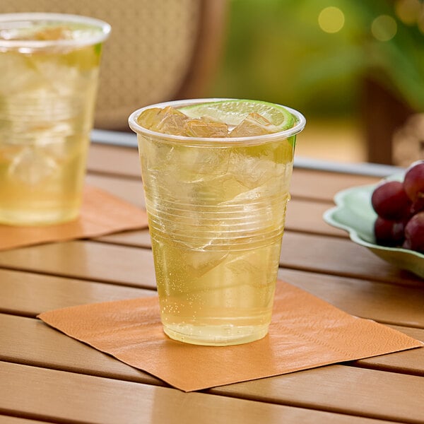 Two Choice translucent plastic cups filled with ice and liquid on a table.