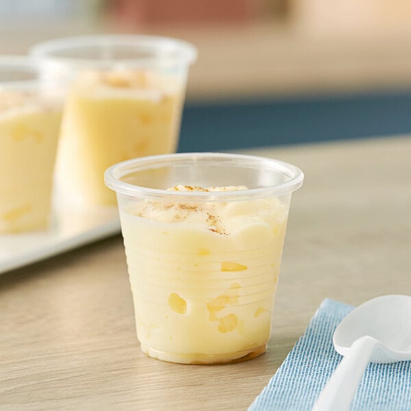 A close-up of a translucent plastic cup filled with pudding.