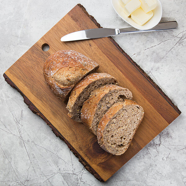 A Tablecraft acacia wood rectangular serving board with sliced bread and butter next to a knife.