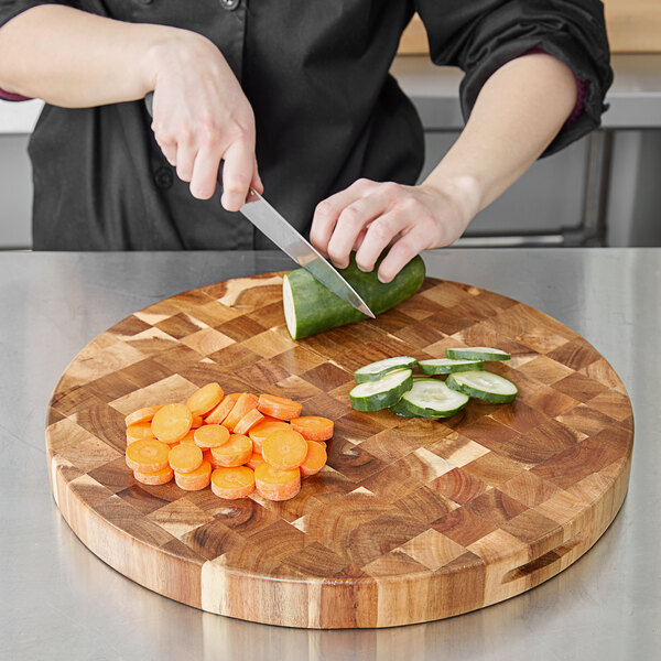 A person cutting vegetables on a Tablecraft acacia wood end grain chopping board.