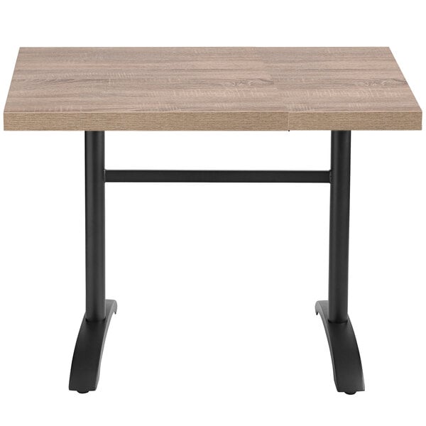 A Grosfillex VanGuard weathered oak resin table top on a table with black legs.