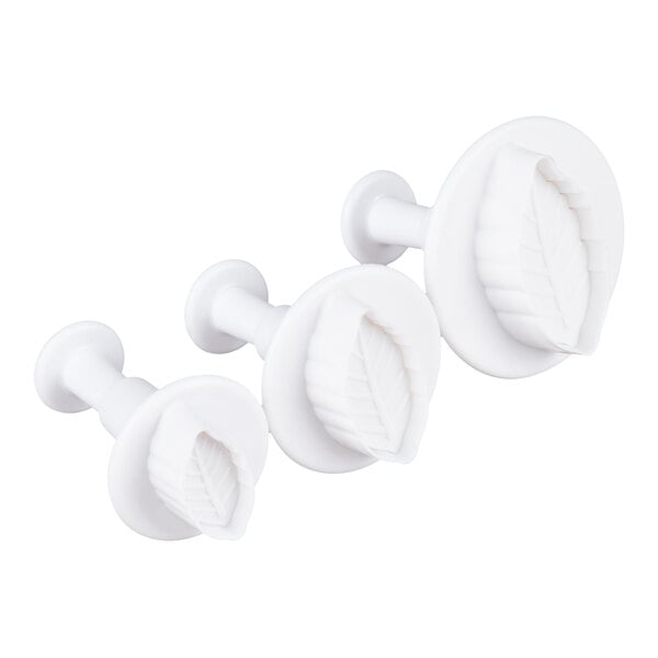 Three white plastic plunger cutters with leaf-shaped designs in different sizes are arranged in a row.