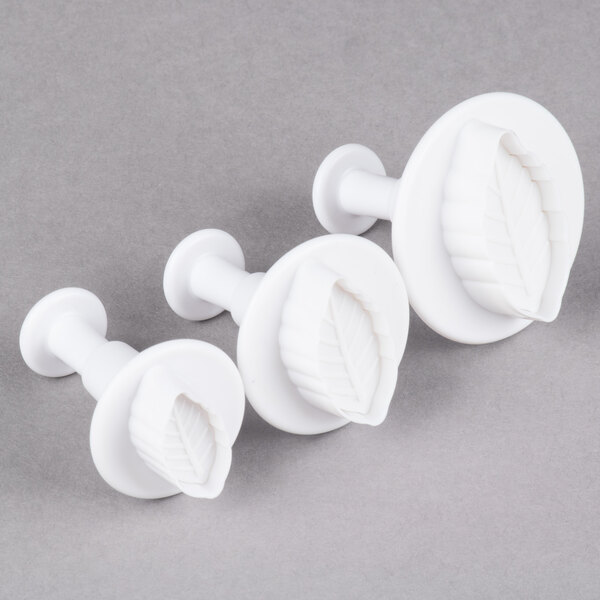 A set of three white plastic leaf-shaped pastry cutters.