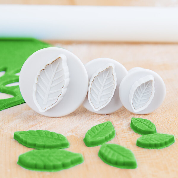 A group of white Ateco leaf shaped cookie cutters.