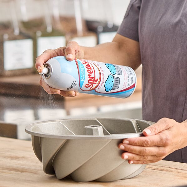 A person spraying Baker's Sprease 16 oz. baking release spray into a bundt cake pan.
