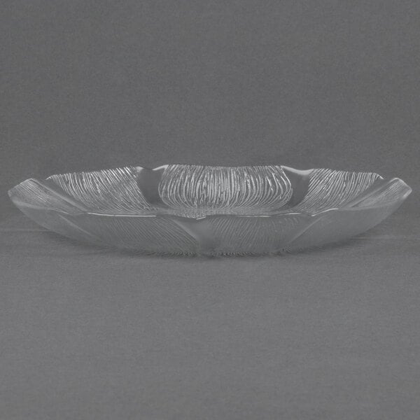 An Arcoroc clear glass Fleur dinner plate on a gray surface.