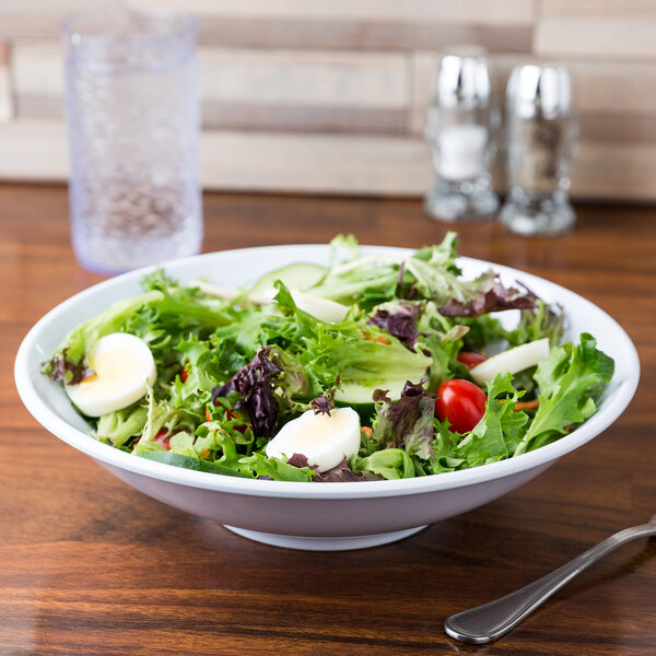 A white melamine bowl with a salad containing eggs and tomatoes.