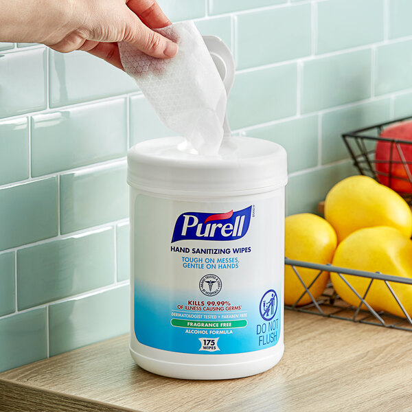 A white Purell container with a blue and white label filled with Purell sanitizing wipes.