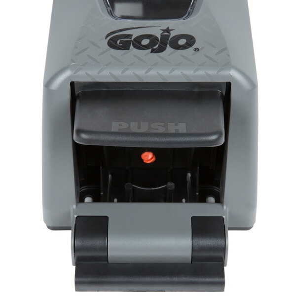 A grey GOJO dispenser with a red push-button.