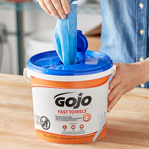 A person removing a GOJO Fast Towel from a bucket.