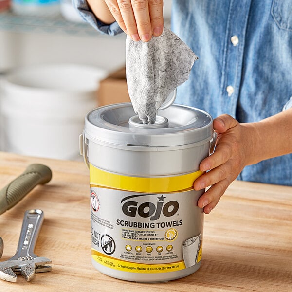 A person removing a scrubbing towel from a bucket.