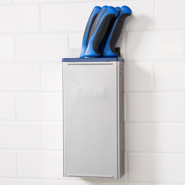 An Edlund stainless steel knife rack with blue inserts holding knives.