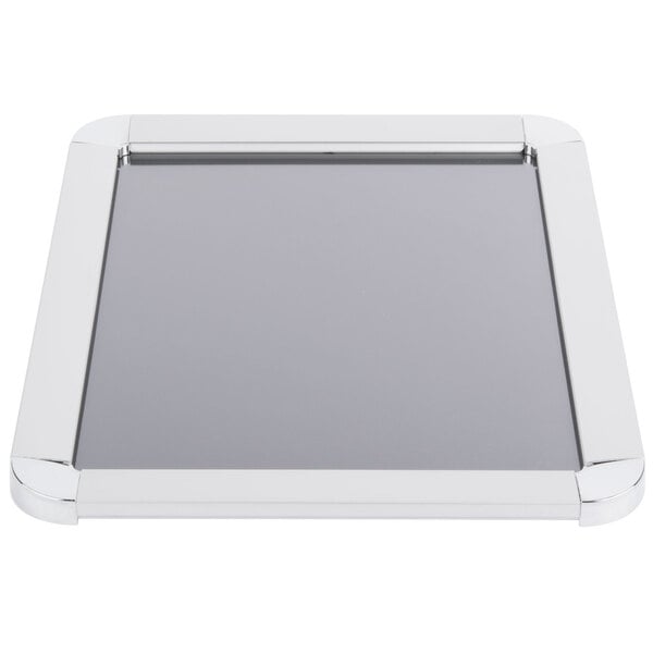 A white rectangular sign frame with a silver border on a black surface.